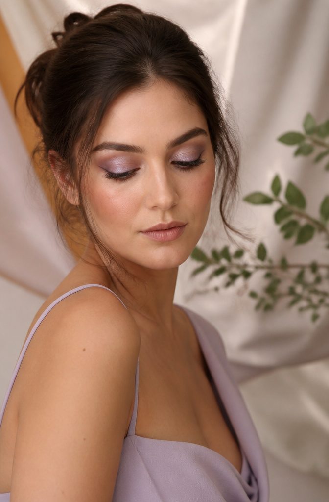 Model showcasing shimmering lavender eye makeup.